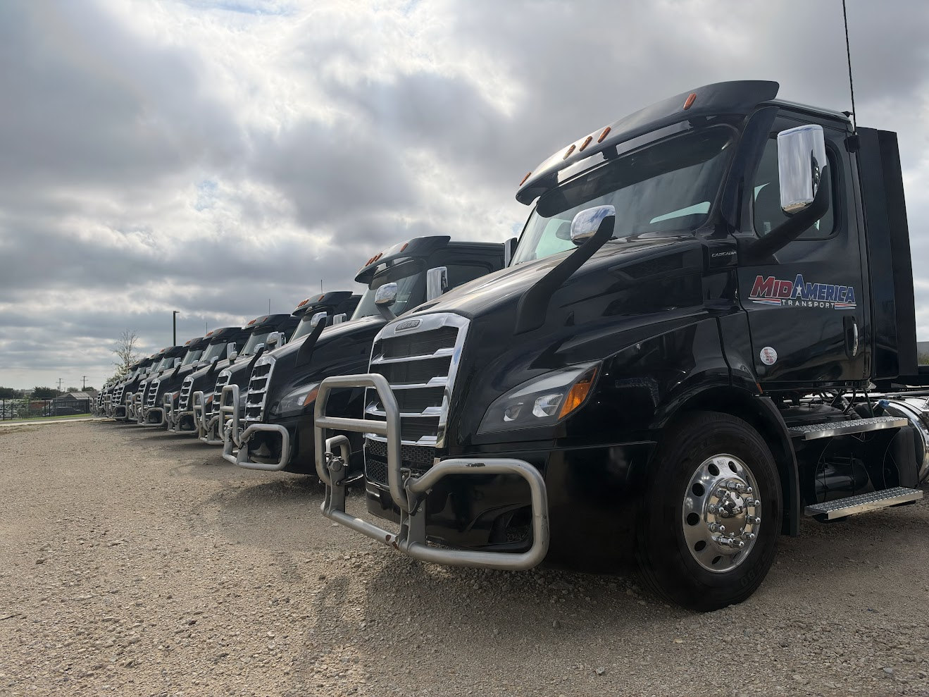 Actual black MidAmerica Transport Freightliner tractors lined up at the staging lot